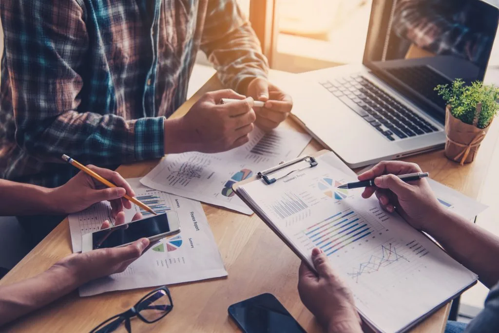 Personen erarbeiten digitale Marketingstrategie am Schreibtisch und analysieren die Insights der Maßnahmen.